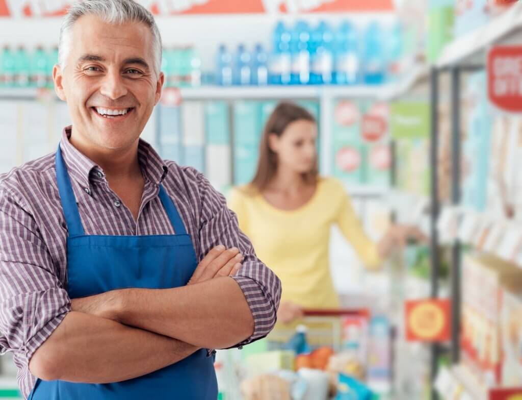 Confident smiling supermarket clerk posing at the shopping mall, retail job concept