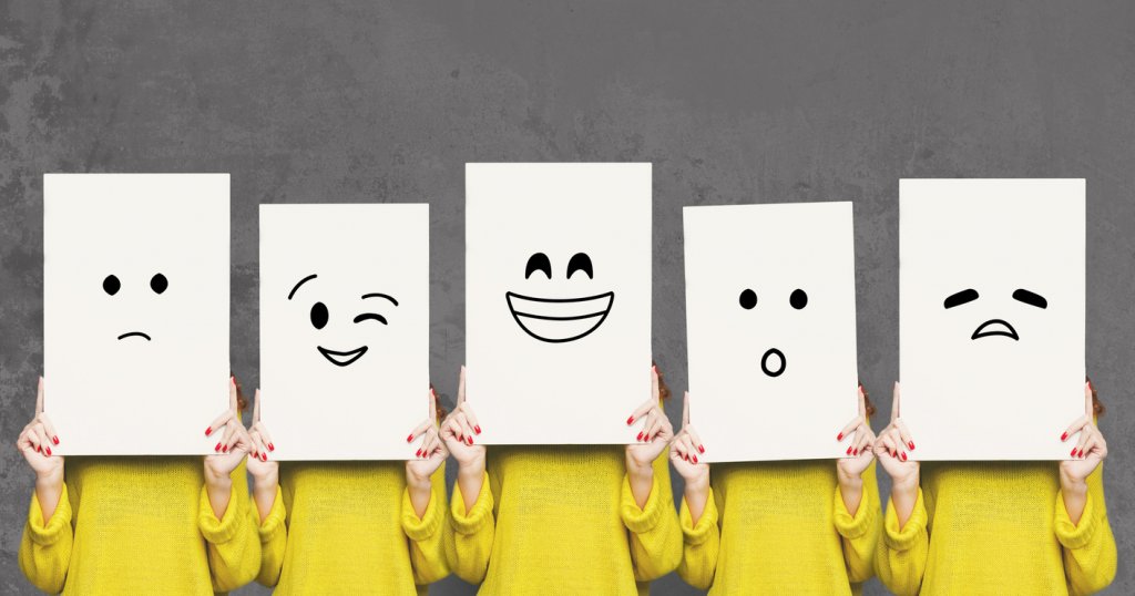 Emotions set. Girl hiding face behind signboard with drawn smileys. Collage of indifferent, winking, happy, surprised, and sad emoticons.