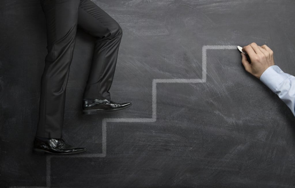 Businessman climbing the career steps drawn on a black chalkboard