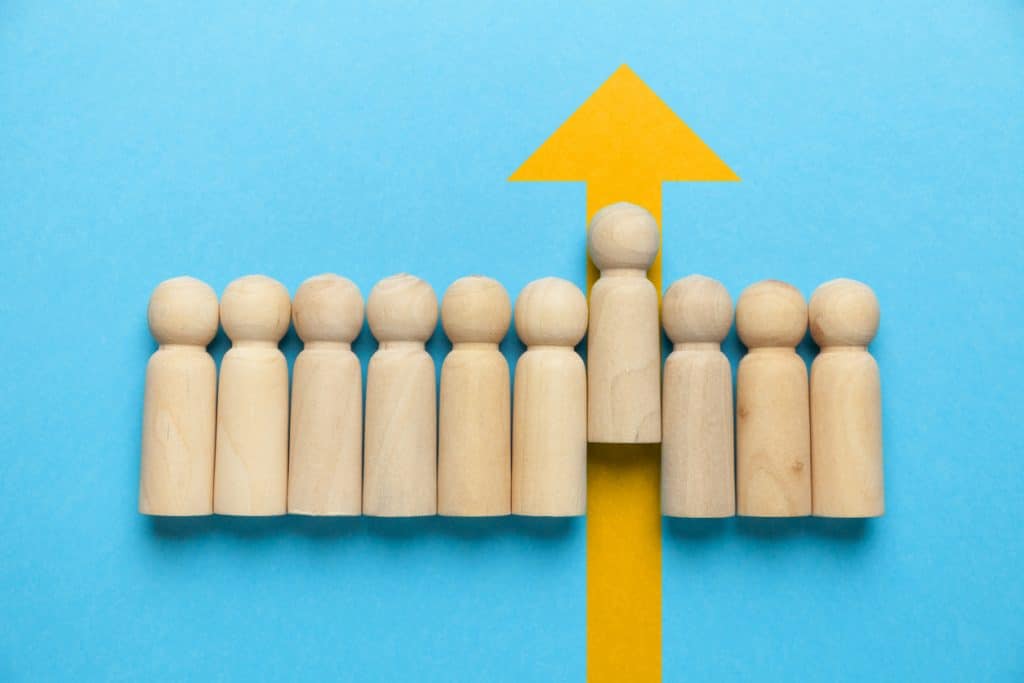 Wooden figures of people with a yellow arrow isolated on a blue background. Career and personal growth, business motivation.