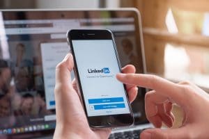 Pessoal segurando celular com logo do Linkedin