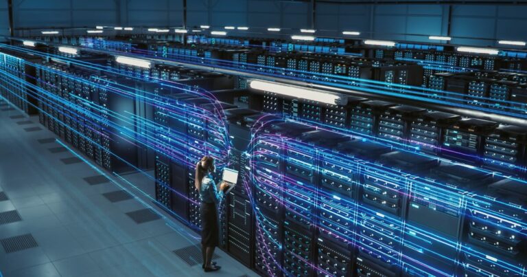 Mulher trabalhando em um grande data center com um laptop, cercada por servidores e representações digitais de fluxos de dados em luzes azuis, simbolizando tecnologia avançada e conectividade (eveo, data center, amazon, austrália, elétrico, energia)