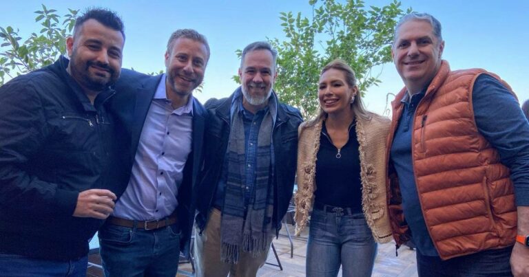 Imagem de um grupo de cinco pessoas em um ambiente ao ar livre, posando lado a lado e sorrindo. Da esquerda para a direita: Ronaldo Gonçalves, Jason Rosenfeld (CEO Global da Cask), Rubens Dalle Lucca (Managing Director LATAM), Bruna Zaroni (Account Executive da Cask) e Giancarlo Montanari (CRO Brazil/SoLA da Cask). O cenário ao fundo inclui árvores e céu claro, transmitindo descontração e profissionalismo