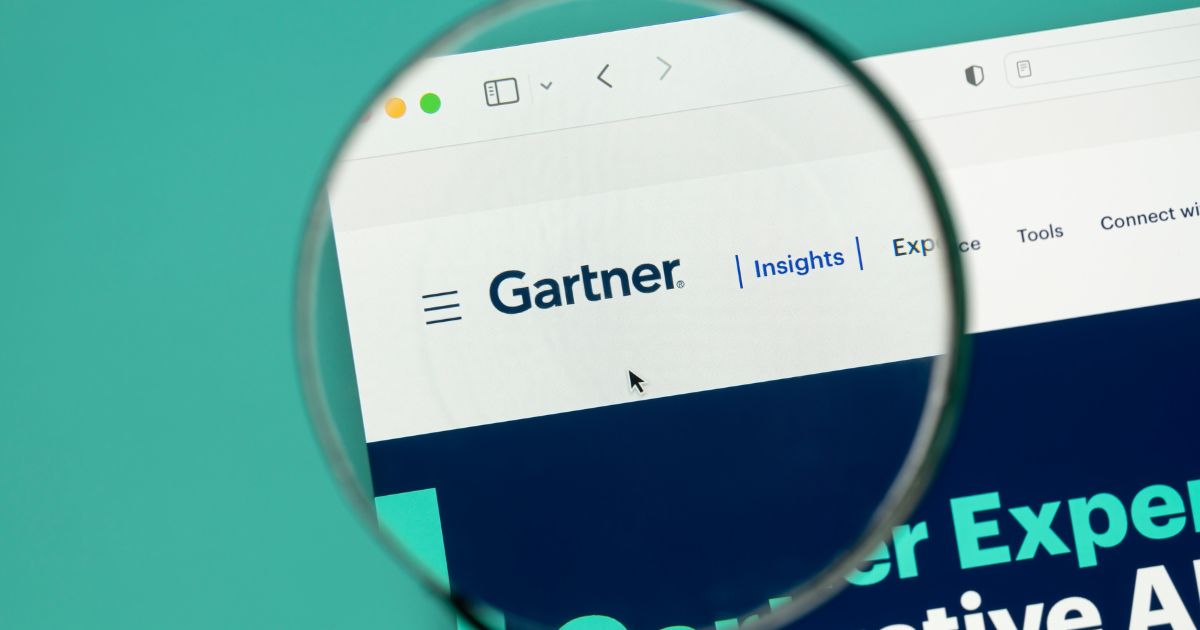 Gastos com IA sobem 49,5% e somam US$ 2,7 tri em 2026, prevê Gartner 4 A imagem mostra o logótipo da empresa "Gartner" em destaque numa página web, visível através de uma lupa. O fundo é predominantemente azul, com texto adicional, mas o foco principal está no logótipo e na barra de navegação do site, que inclui opções como "Insights". O cursor de um rato aparece apontando na interface. O estilo é minimalista e moderno, com cores suaves e uma composição profissional. (gastos, trilhões, 2026)