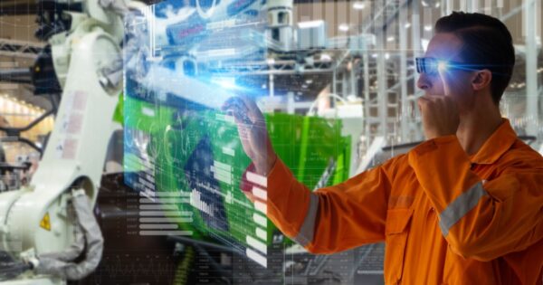 A imagem mostra um trabalhador de uniforme laranja interagindo com uma interface digital em um ambiente industrial. Ele usa óculos inteligentes e está manipulando gráficos e dados virtuais que flutuam diante dele, representando a tecnologia de gêmeos digitais. No fundo, pode-se ver um braço robótico industrial e uma linha de produção. A cena sugere o uso de tecnologias avançadas para monitoramento e controle de processos de manufatura (digital twin, gemeos digitais, indústria, fábrica, manufatura, Autodesk)