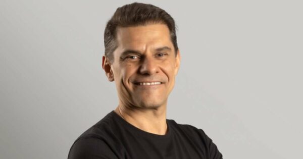 Paulo Secco, CEO da Mignow, sorrindo em um retrato de meio corpo com fundo neutro, vestindo uma camisa preta