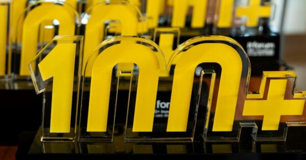 A imagem mostra um troféu translúcido com detalhes em amarelo, representando o prêmio "100+ Inovadoras", concedido a empresas destacadas por sua inovação. O design do troféu apresenta o número "100+" em um estilo moderno e arrojado. No fundo, há outros troféus idênticos, sugerindo um evento de premiação (empresas, IT Forum, prêmio)