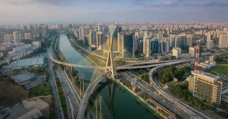 Vista aérea da cidade de São Paulo, destacando a Ponte Estaiada Octavio Frias de Oliveira, um dos principais cartões-postais da capital paulista. A ponte cruza o Rio Pinheiros e conecta importantes vias, como a Marginal Pinheiros. Ao fundo, vê-se a região da Berrini e Vila Olímpia, com diversos prédios comerciais modernos, mostrando o centro financeiro da cidade. (sao paulo, sp, ponte estaiada, marginal pinheiros, berrini, vila olimpia, SP, governo, prefeitura)
