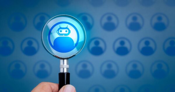 Imagem conceptual de seleção de perfis com foco em inteligência artificial. Uma mão segura uma lupa que destaca um ícone de robô azul dentro de um círculo, representando um perfil de IA. Ao fundo, vários ícones semelhantes de perfis humanos aparecem desfocados, também em tons de azul. A lupa simboliza a escolha ou identificação de uma inteligência artificial entre perfis humanos. bots