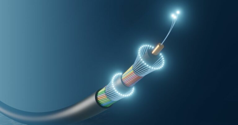 Imagem ilustrativa de um cabo submarino de fibra óptica, utilizado em telecomunicações. A imagem mostra o cabo cortado em perspectiva para exibir sua estrutura interna, com várias camadas de proteção e múltiplas fibras ópticas brilhando em azul, indicando a transmissão de dados por luz. O fundo azul escuro simula o ambiente subaquático (cabo submarino, fibra óptica, telecomunicações, ceará)