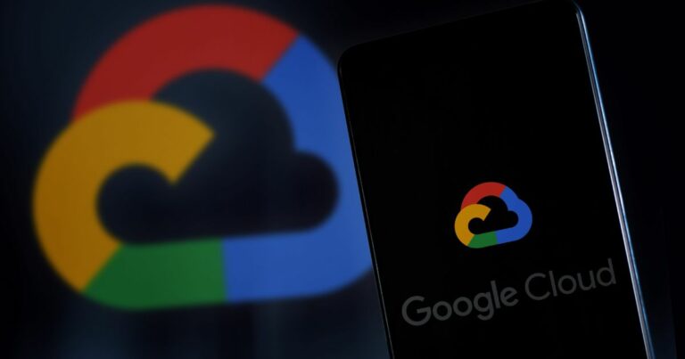 Imagem de um smartphone com a tela exibindo o logotipo do Google Cloud, composto por uma nuvem estilizada com as cores azul, vermelho, amarelo e verde características do Google. Ao fundo, o mesmo logotipo aparece em tamanho ampliado e desfocado, compondo o fundo escuro da imagem. A palavra “Google Cloud” aparece parcialmente na parte inferior da tela do celular. A composição destaca o tema de serviços em nuvem e tecnologia (governança)
