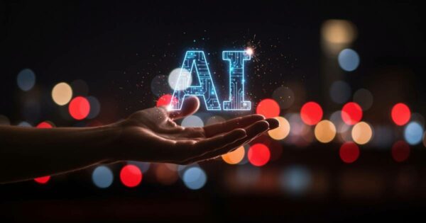 Mão estendida em primeiro plano segurando uma representação digital iluminada das letras “AI”, sigla em inglês para inteligência artificial, com circuitos eletrônicos visíveis no interior das letras. Ao fundo, luzes desfocadas coloridas criam um ambiente noturno urbano. A imagem simboliza o desenvolvimento e o avanço da inteligência artificial. (desenvolvimento, desenvolve, pesquisa, apple, empresas, investimento)
