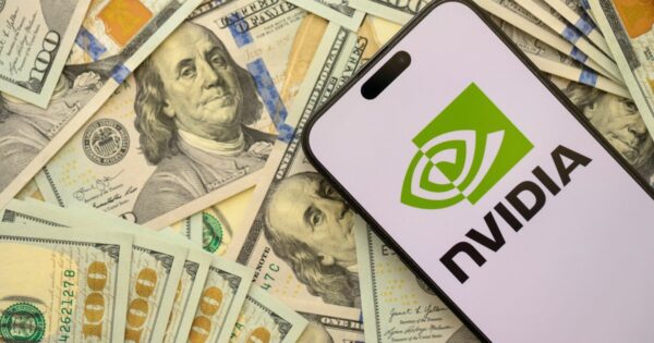 Um smartphone exibe o logotipo da NVIDIA e está posicionado sobre uma pilha de notas de 100 dólares americanos.