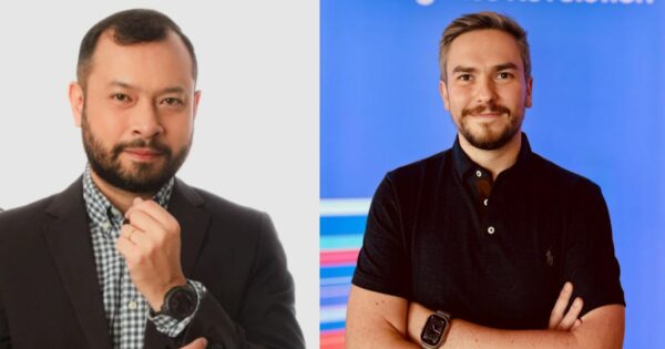 A imagem apresenta duas pessoas com os rostos desfocados. À esquerda, uma pessoa veste um terno preto sobre uma camisa xadrez e segura o queixo com a mão direita, onde é visível um relógio de pulso preto. O fundo atrás dela é branco. À direita, outra pessoa aparece com os braços cruzados, usando uma camisa polo preta com botões e também um relógio de pulso preto. O fundo dessa parte da imagem é azul, com algumas listras coloridas visíveis à esquerda da pessoa. (Fico)