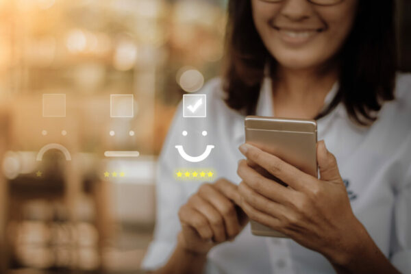 Pessoa sorridente usando smartphone para avaliar o atendimento ou serviço, com elementos de avaliação digital e estrelas. (anima)