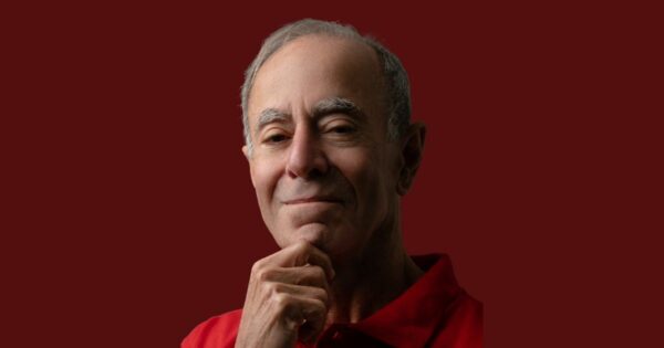 Cezar Taurion, consultor de tecnologia, usando camisa polo vermelha, com expressão confiante e mão apoiada no queixo, sobre fundo vermelho sólido (soberania digital)