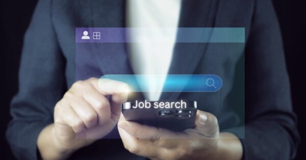 Uma pessoa segura um smartphone e interage com uma barra de busca virtual que exibe o texto "Job search". A imagem representa o conceito de busca por oportunidades de emprego online.