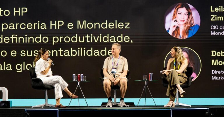 Três pessoas estão sentadas em um palco participando de uma discussão em painel. Ao fundo, um telão exibe o texto: "parceria HP e Mondelez definindo produtividade, e sustentabilidade global". Também aparecem os nomes e cargos de duas participantes: "Leila Zim – CIO da Mondelez" e "Deb Mo – Diretora de Marketing".