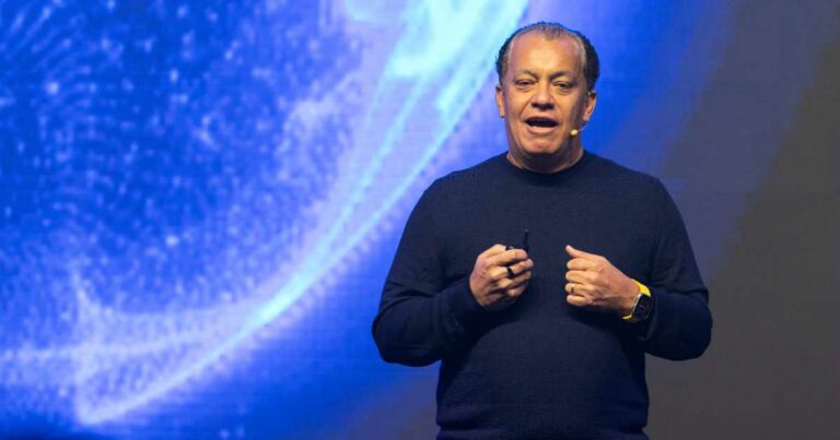 Roberto Oliveira, CEO da Blip, falando no palco durante o evento Blip ID 2025, com fundo azul iluminado e microfone de lapela.