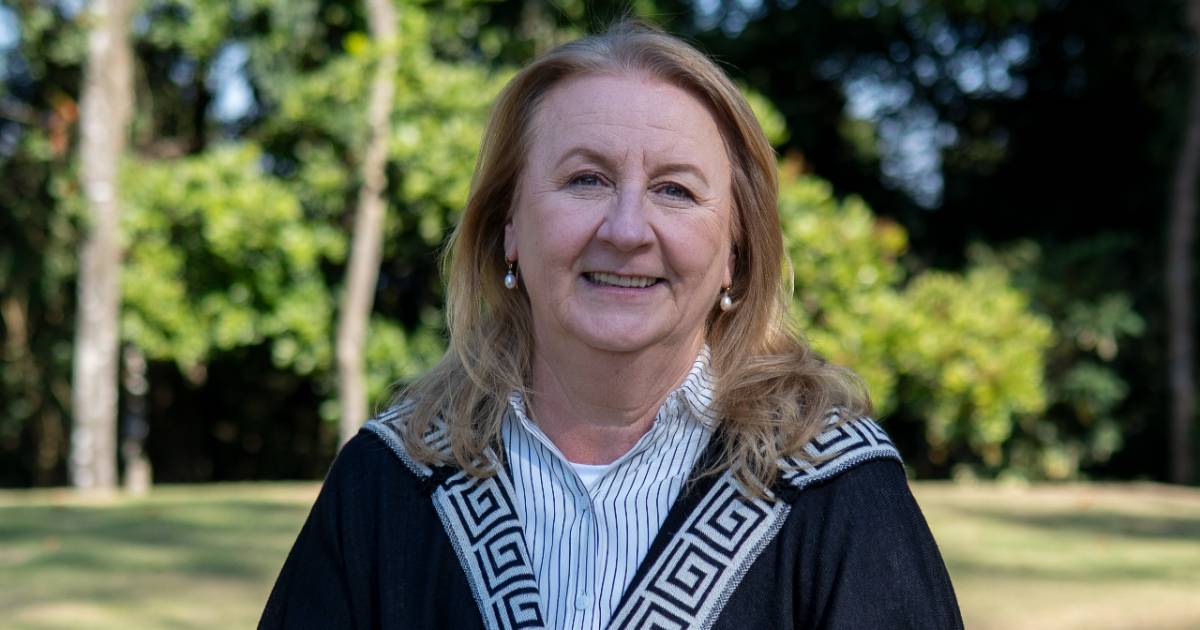 Mulher sorridente, identificada como Walkiria Marchetti, executiva de tecnologia ex-Bradesco, em foto ao ar livre com árvores ao fundo. Ela usa camisa listrada clara e casaco escuro com detalhes geométricos na gola.
