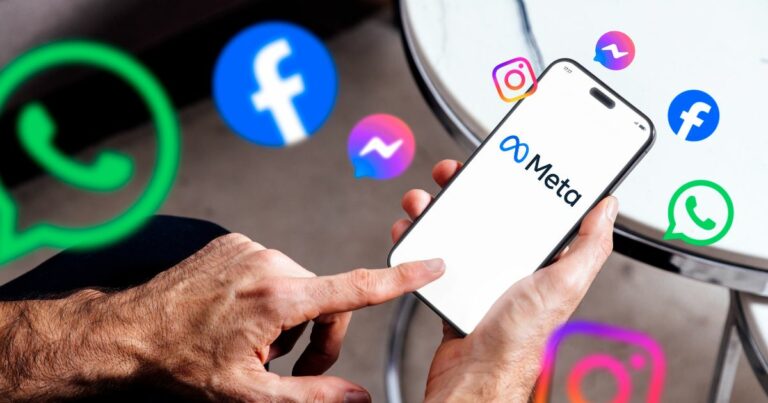 A imagem mostra uma mão segurando um smartphone que exibe o logotipo da Meta em destaque, com o texto “Meta” e o símbolo característico da empresa. Ao redor do dispositivo, há ícones flutuantes representando os principais aplicativos do ecossistema Meta: WhatsApp (ícones verdes com balão de conversa) Facebook (ícones azuis com a letra “f”) Instagram (ícones coloridos em tons de rosa, roxo e laranja) Messenger (ícones azuis com balão de mensagem) O fundo é neutro, com uma mesa metálica parcialmente visível, sugerindo um ambiente casual ou corporativo. A composição transmite a ideia de conectividade e integração entre as plataformas da Meta, reforçando sua presença no universo digital. redes sociais (ECA Digital)