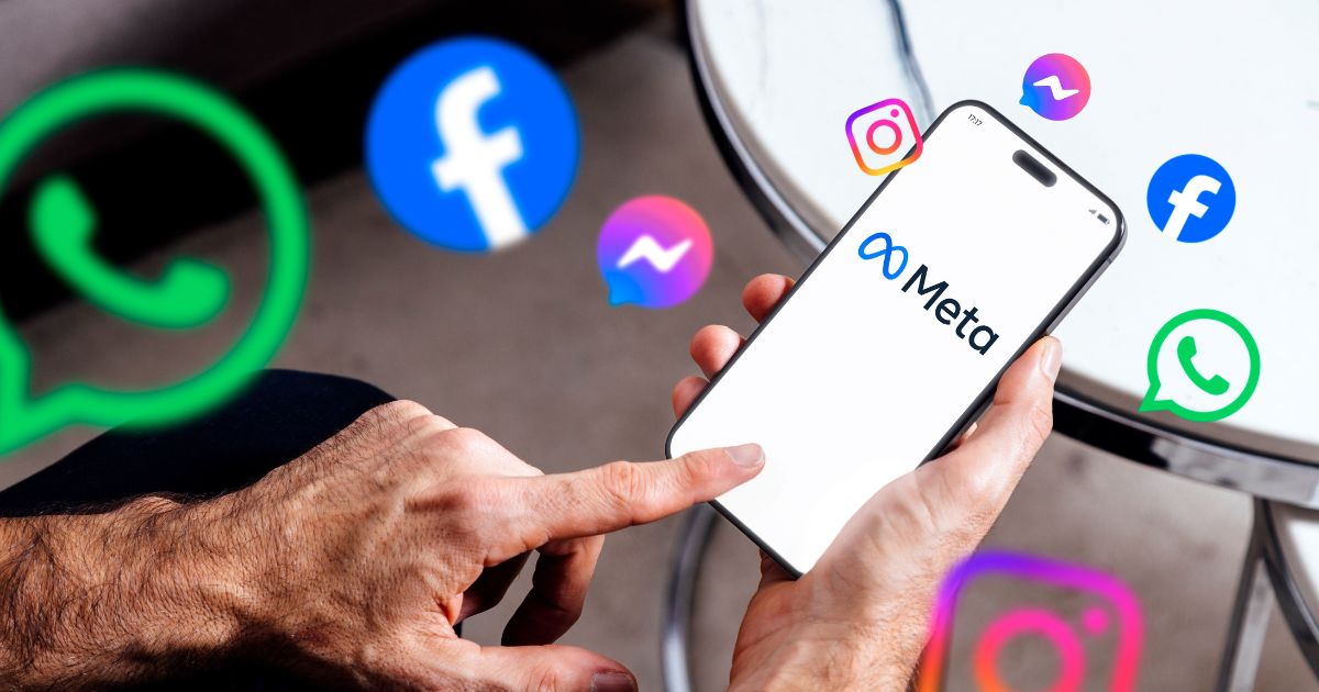 A imagem mostra uma mão segurando um smartphone que exibe o logotipo da Meta em destaque, com o texto “Meta” e o símbolo característico da empresa. Ao redor do dispositivo, há ícones flutuantes representando os principais aplicativos do ecossistema Meta: WhatsApp (ícones verdes com balão de conversa) Facebook (ícones azuis com a letra “f”) Instagram (ícones coloridos em tons de rosa, roxo e laranja) Messenger (ícones azuis com balão de mensagem) O fundo é neutro, com uma mesa metálica parcialmente visível, sugerindo um ambiente casual ou corporativo. A composição transmite a ideia de conectividade e integração entre as plataformas da Meta, reforçando sua presença no universo digital. redes sociais (ECA Digital)