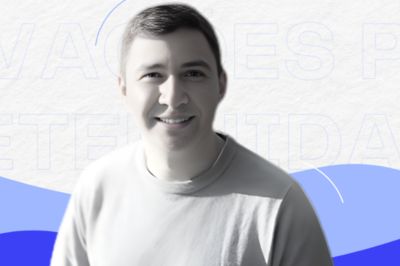Pessoa vestindo camiseta clara, posicionada diante de um fundo gráfico com formas abstratas em azul e branco, criando uma composição moderna e visualmente limpa.