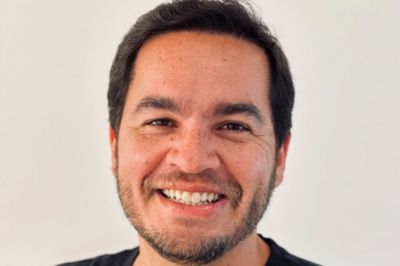 Pessoa vestindo roupa escura, em enquadramento fechado, contra um fundo neutro, com composição simples e foco no vestuário.
