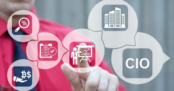 A imagem mostra uma pessoa vestindo uma camisa vermelha, interagindo com ícones digitais exibidos em balões translúcidos. Os ícones representam conceitos corporativos e de gestão, incluindo: Um símbolo de porcentagem com uma lupa (análise financeira ou taxas). Um ícone de prancheta com marca de verificação (tarefas ou checklist). Um ícone de mão segurando cifrão (gestão financeira ou investimentos). Um ícone de pessoa diante de um quadro (treinamento ou apresentação). Um ícone de edifício corporativo (empresa ou infraestrutura). Um balão com a sigla CIO (Chief Information Officer). O fundo é neutro e desfocado, destacando os elementos gráficos. A composição transmite temas relacionados a liderança, tecnologia, gestão empresarial e tomada de decisão estratégica. (CISO)