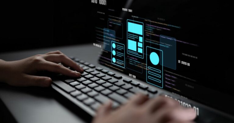 A imagem mostra um teclado sendo utilizado por uma pessoa, com uma tela digital projetando elementos gráficos e códigos. Detalhes principais: Primeiro plano: Mãos digitando em um teclado, sugerindo atividade de programação ou desenvolvimento. Tela projetada: Exibe códigos em linguagem de programação e elementos de interface (UI) como caixas, ícones e layouts, indicando design e desenvolvimento de aplicações ou sites. Cores e estilo: Fundo escuro com destaques em azul neon para os elementos gráficos, transmitindo uma estética tecnológica e futurista. Contexto: Representa claramente um cenário de desenvolvimento digital, programação e inovação tecnológica. (BRQ) Forrester