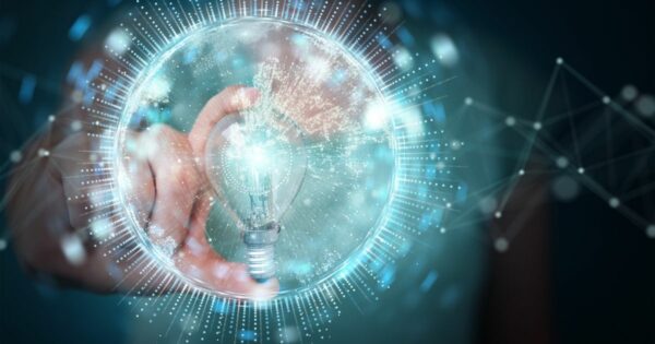 A imagem mostra uma mão segurando uma lâmpada dentro de uma esfera translúcida com efeitos luminosos ao redor, criando uma aparência futurista e tecnológica. Linhas e pontos conectados se estendem para fora da esfera, sugerindo conceitos de inovação, ideias e redes digitais. A iluminação é predominantemente azul e branca, com brilho intenso destacando a lâmpada como símbolo central de criatividade e soluções inteligentes. O fundo é abstrato, reforçando a temática de tecnologia e conexão. (inovação)
