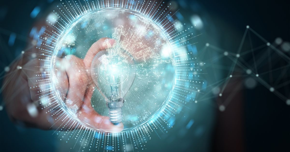 A imagem mostra uma mão segurando uma lâmpada dentro de uma esfera translúcida com efeitos luminosos ao redor, criando uma aparência futurista e tecnológica. Linhas e pontos conectados se estendem para fora da esfera, sugerindo conceitos de inovação, ideias e redes digitais. A iluminação é predominantemente azul e branca, com brilho intenso destacando a lâmpada como símbolo central de criatividade e soluções inteligentes. O fundo é abstrato, reforçando a temática de tecnologia e conexão. (inovação)