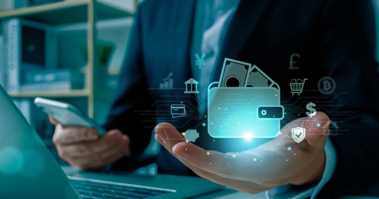 A imagem apresenta um conceito visual relacionado a finanças digitais e tecnologia. Detalhes principais: Elemento central: Uma mão aberta com uma sobreposição digital mostrando um ícone de carteira eletrônica contendo notas de dinheiro. Ao redor da carteira, há ícones que representam diferentes aspectos financeiros, como: Símbolos monetários (dólar, libra, iene, bitcoin). Ícones de segurança (escudo com check). Carrinho de compras (e-commerce). Gráficos e indicadores financeiros. Contexto físico: A pessoa segura um smartphone na outra mão, sugerindo uso de aplicativos financeiros ou pagamentos digitais. Um laptop está parcialmente visível sobre a mesa, reforçando a ideia de integração tecnológica. Traje formal (terno), indicando um ambiente corporativo ou profissional. Cores e iluminação: Tons escuros no cenário físico contrastando com os elementos digitais em azul neon, criando uma estética futurista e tecnológica. Essa imagem transmite inovação em serviços financeiros, transformação digital, segurança e praticidade nos pagamentos online. (crédito, cielo)
