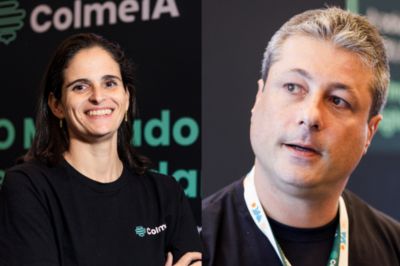 Duas pessoas usando camisetas pretas com logotipo da ColmeIA, em frente a um painel escuro de eventos ou conferências.