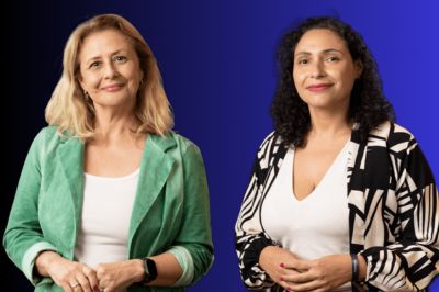 Duas pessoas posando diante de um fundo azul; uma usa blazer verde e a outra um cardigã estampado em preto e branco.