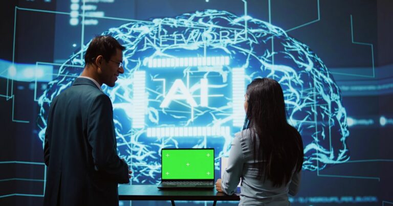 Duas pessoas observam uma grande projeção digital que exibe a ilustração de um cérebro formado por circuitos e linhas luminosas em azul, com a palavra “AI” ao centro. À frente delas, há um notebook aberto sobre uma mesa, com a tela em verde sólido, sugerindo uso de chroma key. O ambiente tem aparência tecnológica e imersiva, como uma demonstração ou apresentação de sistemas de inteligência artificial. (seguradora)