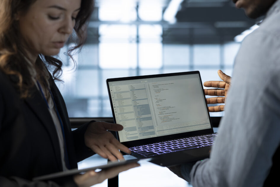 Software developers in data center workspace use laptop to calibrate energy usage. Server room IT professionals code on notebook, doing maintenance on equipment mainframes