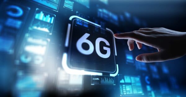 Imagem de uma interface digital futurista em tons de azul, exibindo o texto “6G” no centro de um painel luminoso. À direita, uma mão humana se aproxima da tela com o dedo estendido, como se estivesse prestes a tocar ou ativar o painel. Ao fundo, há diversos gráficos, diagramas e telas flutuantes com dados e visualizações tecnológicas, sugerindo conectividade avançada, redes de comunicação e inovação. O conjunto transmite a ideia de tecnologia de próxima geração e interação homem-máquina, cpqd