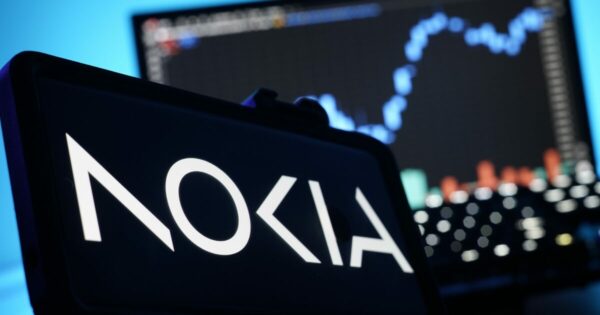 Imagem para simbolizar o aumento das ações da Nokia, tem um celular com o logo da empresa e um notebook atrás com um gráfico em crescimento.