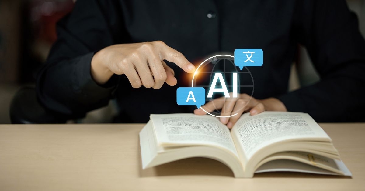 Pessoa sentada à mesa com um livro aberto à sua frente. Uma das mãos aponta para um elemento gráfico sobreposto ao livro, com a sigla ‘AI’ no centro de um círculo luminoso. Ao redor da sigla aparecem pequenos ícones de balões de texto com caracteres, sugerindo tradução ou processamento de linguagem. O fundo é escuro e desfocado, destacando o livro, as mãos e o elemento digital. (alfabetiza)