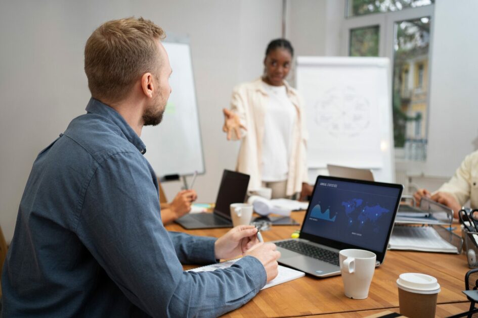 Equipe corporativa em reunião de negócios em escritório moderno, com apresentação estratégica e análise de dados em notebook. Ambiente colaborativo de trabalho, treinamento empresarial e tomada de decisão em equipe.