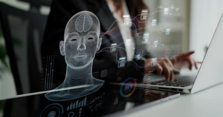 Pessoa utilizando um computador portátil em uma mesa, vista parcialmente ao fundo. Em primeiro plano, há uma sobreposição gráfica translúcida com a representação de uma cabeça humana em estilo wireframe, mostrando o cérebro em destaque. Ao redor da figura aparecem painéis digitais flutuantes com ícones, gráficos circulares, barras, porcentagens e blocos conectados por linhas, sugerindo processamento de dados e sistemas digitais. O ambiente tem iluminação suave, com fundo desfocado que mantém o foco nos elementos tecnológicos. (Brasil)