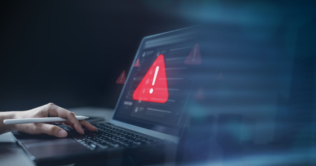 Tela de notebook exibindo alerta de segurança digital com ícone de perigo, representando firewall, cibersegurança e proteção de dados.