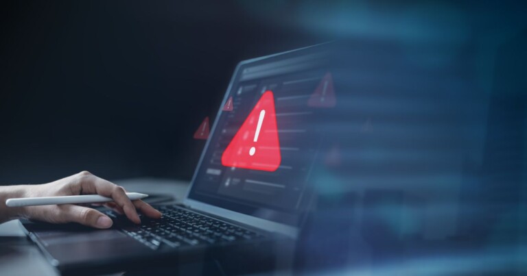 Tela de notebook exibindo alerta de segurança digital com ícone de perigo, representando firewall, cibersegurança e proteção de dados.