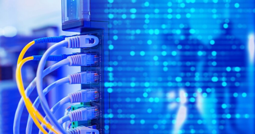 Conexões de fibra óptica ligadas a equipamento de rede em ambiente tecnológico. Imagem relacionada a data centers, infraestrutura de telecomunicações, conectividade corporativa, transmissão de dados em alta velocidade, redes de alta capacidade e transformação digital.