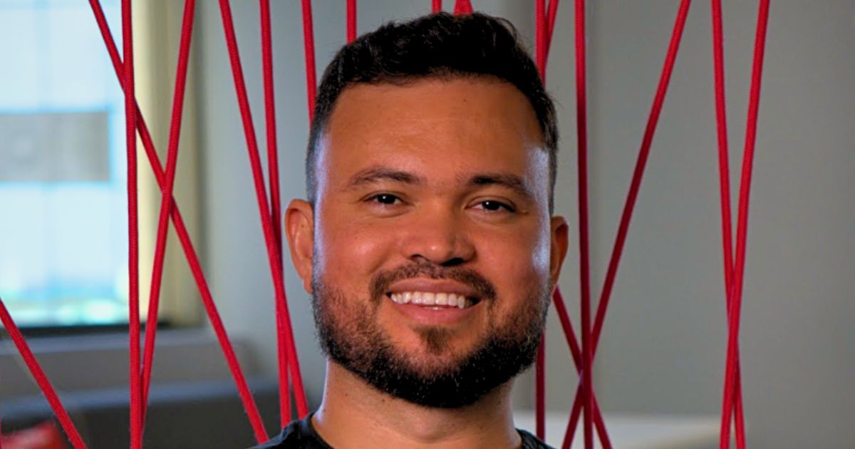 Retrato profissional do Jamilson Batista, diretor de Tecnologia Logística do IFood em ambiente corporativo, com fundo moderno e elementos decorativos vermelhos no escritório.