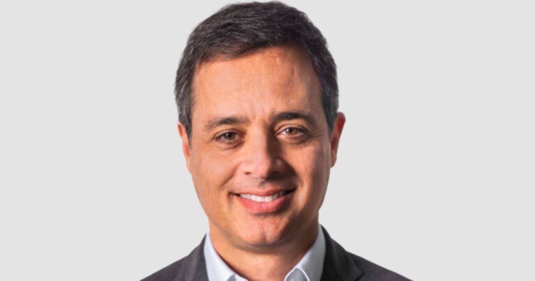 Foto de perfil corporativo profissional mostrando uma pessoa em enquadramento frontal, vestindo blazer escuro e camisa clara, sobre fundo cinza neutro. Imagem utilizada para apresentações executivas, páginas institucionais e perfis corporativos. (Microsoft)