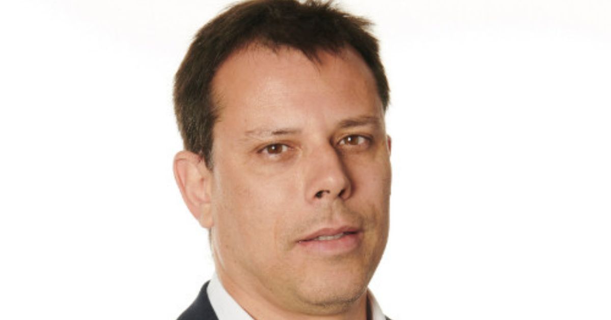 Retrato corporativo em close-up de uma pessoa posicionada diante de um fundo branco. A imagem mostra principalmente o rosto e parte dos ombros, com enquadramento próximo e foco nítido nos traços faciais. A pessoa veste paletó escuro sobre uma camisa clara. O fundo é uniforme e sem elementos decorativos, destacando a figura em primeiro plano. A iluminação é suave e distribuída de maneira homogênea, conferindo aspecto profissional e institucional à fotografia. (Sucafina)