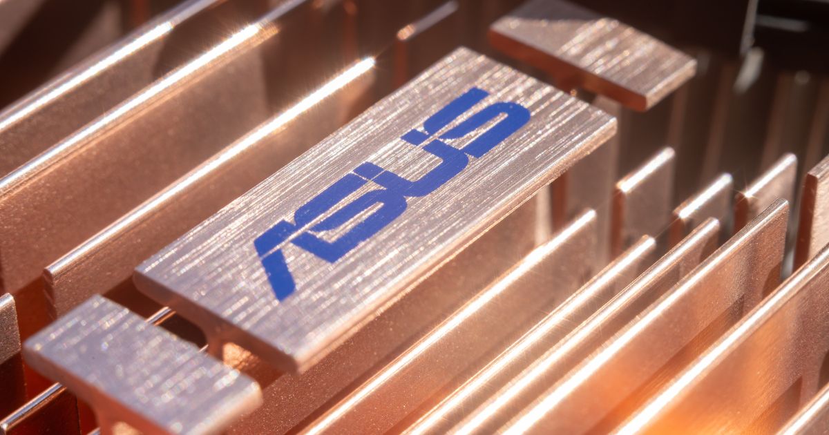 ASUS Business completa 1 ano de operação no Brasil com meta de alcançar top 3 entre fabricantes de PCs até 2030 2 Imagem em close-up de um componente metálico com a marca ASUS gravada em azul sobre uma superfície de alumínio escovado. A peça faz parte de uma estrutura composta por diversas lâminas metálicas paralelas, semelhantes a um dissipador de calor utilizado em equipamentos eletrônicos. A iluminação quente cria reflexos dourados nas superfícies metálicas, destacando as texturas e os detalhes do acabamento. O enquadramento enfatiza a engenharia e os materiais do componente, associando a imagem a hardware, tecnologia e desempenho computacional.