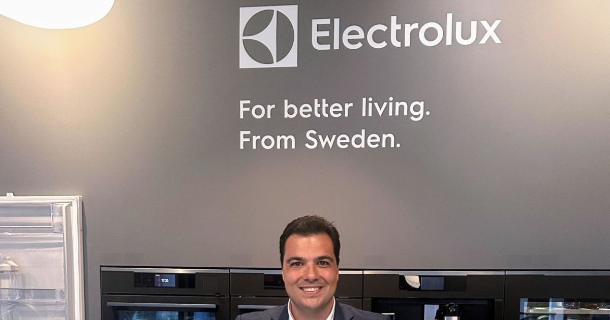 Leonardo Sotocorno assume como CIO EMEA e APAC do Grupo Electrolux 6 Fotografia realizada em um ambiente de exposição ou showroom da Electrolux. Ao fundo, uma parede cinza exibe o logotipo da marca e o texto em inglês: “Electrolux. For better living. From Sweden.”. Na parte inferior da imagem, uma pessoa está posicionada em frente a uma linha de eletrodomésticos embutidos com acabamento escuro. À esquerda, é possível observar um refrigerador ou vitrine com porta transparente. O espaço possui iluminação uniforme e design moderno, destacando os produtos e a identidade visual da marca. A composição remete a um evento corporativo, demonstração de produtos ou ambiente institucional do setor de eletrodomésticos.